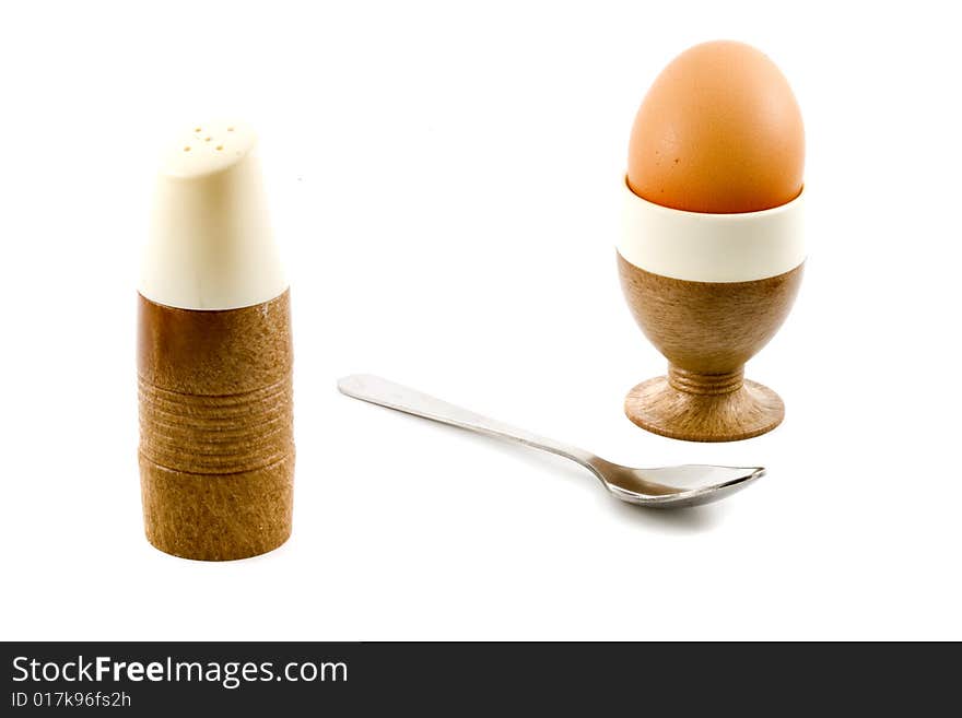 A soft boiled egg, a spoon and a saltpot