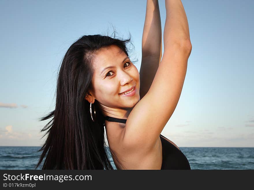 Young Vietnamese female lifting her arms with a blue sky background. Young Vietnamese female lifting her arms with a blue sky background.