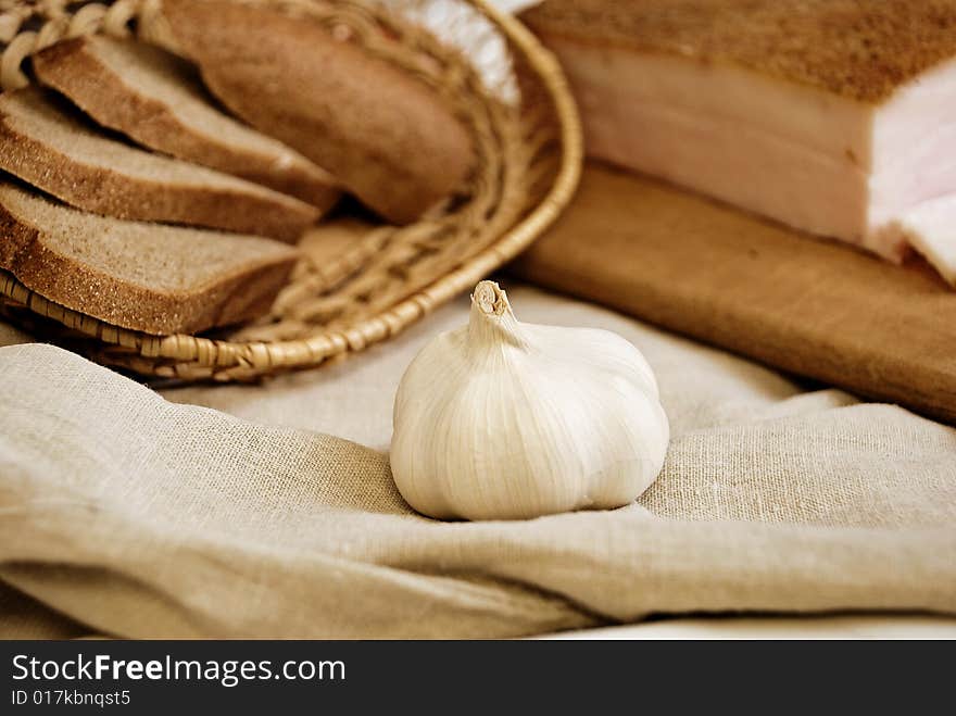 Garlic in focus, bread and bacon as background