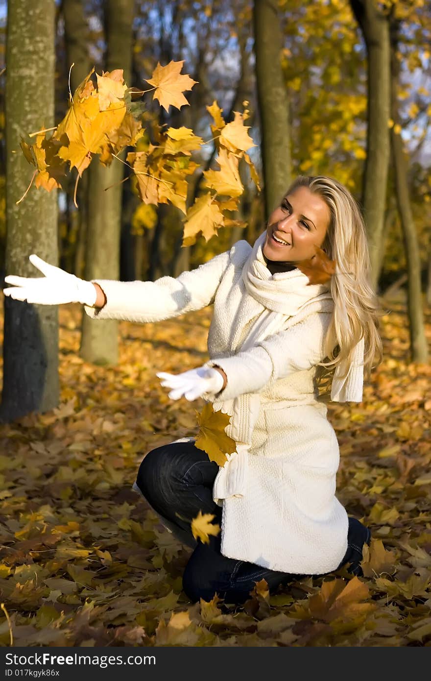 Girl in the park throwing up maple leaves. Girl in the park throwing up maple leaves