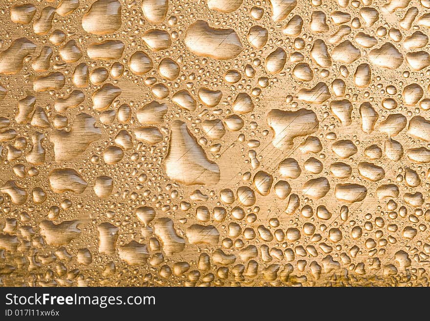 Golden water drops over brushed metal background. Golden water drops over brushed metal background