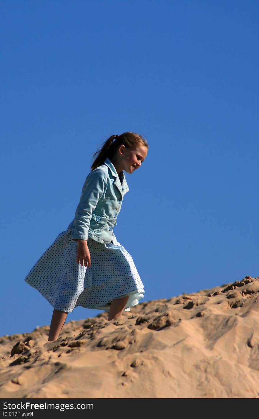 A white caucasian girl child playing on a sand dune on a hot summers day. A white caucasian girl child playing on a sand dune on a hot summers day