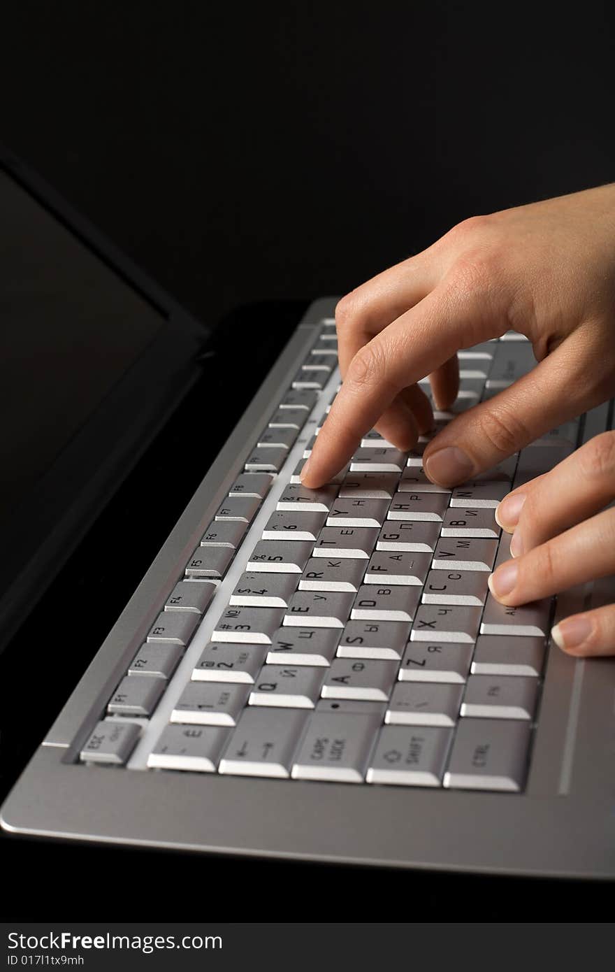 Fingers over notebook keyboard over black background