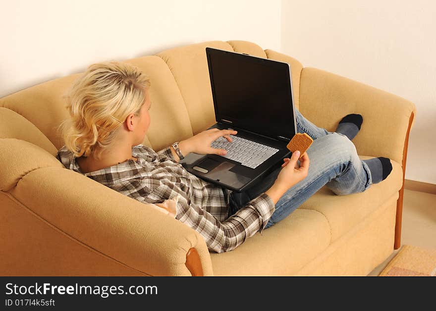 Young woman working with her laptop, sitting on a sofa. Young woman working with her laptop, sitting on a sofa.