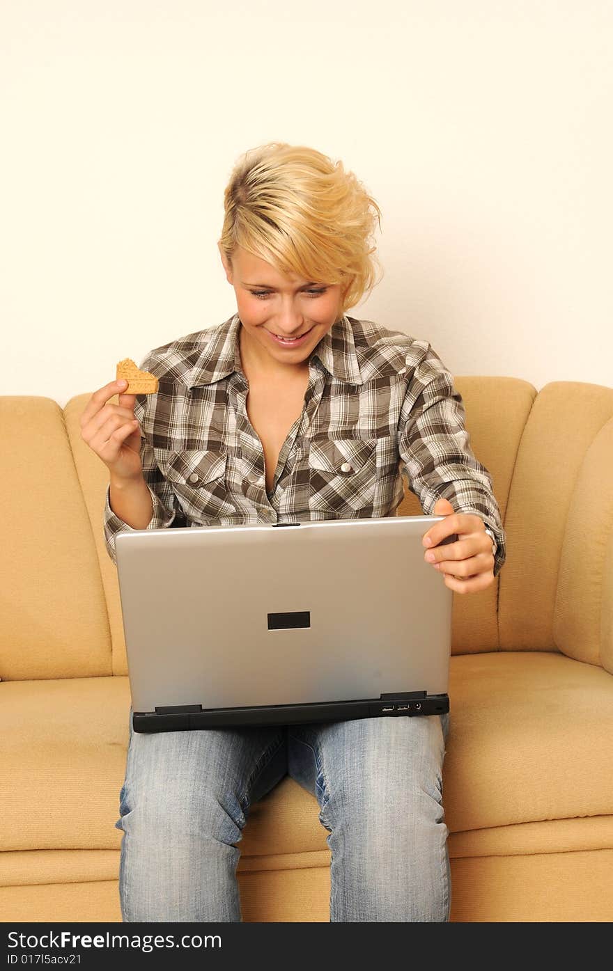 Young woman working with her laptop, sitting on a sofa. Young woman working with her laptop, sitting on a sofa.