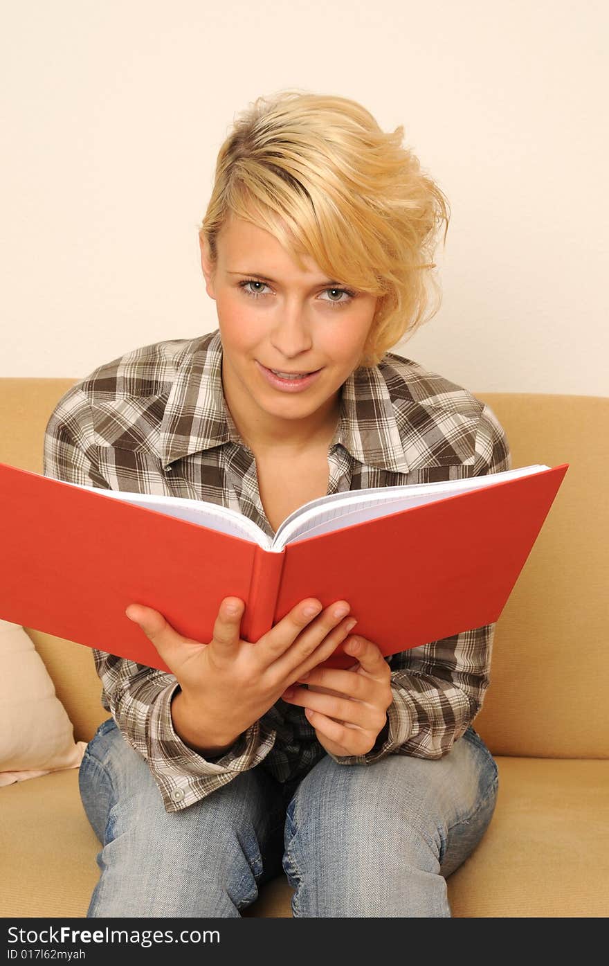 Young woman reading a book, sitting on a sofa. Young woman reading a book, sitting on a sofa.