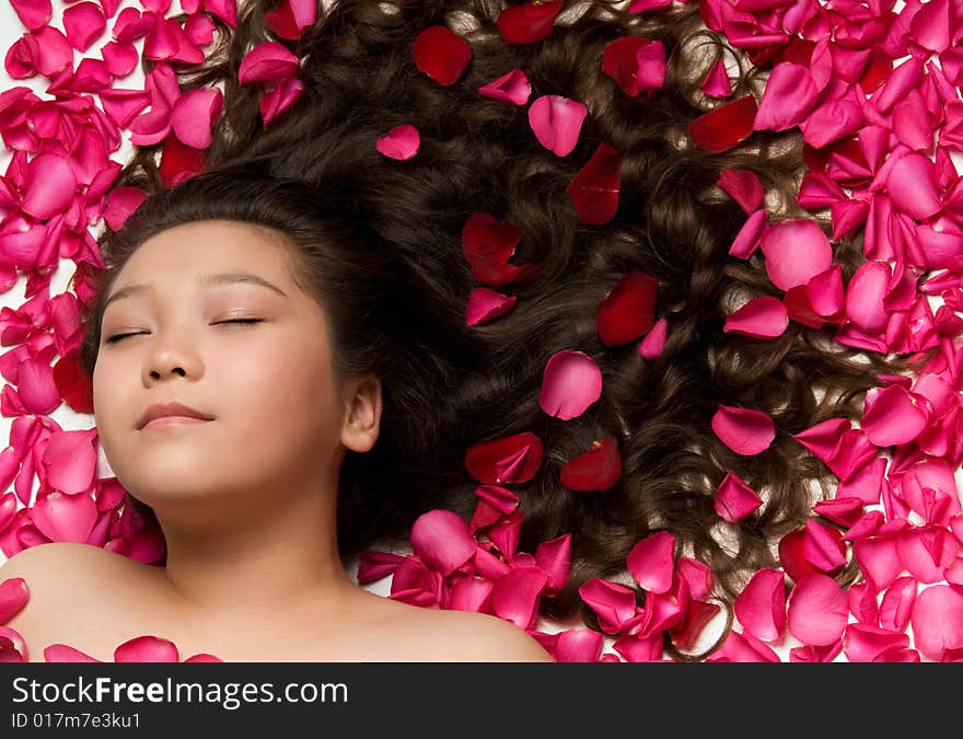 Asian girl with long hair and rose petals