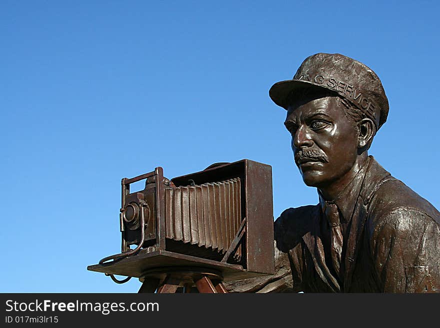 A Statue of a photographer using a Korona-V vintage camera to take a photograph. A Statue of a photographer using a Korona-V vintage camera to take a photograph.