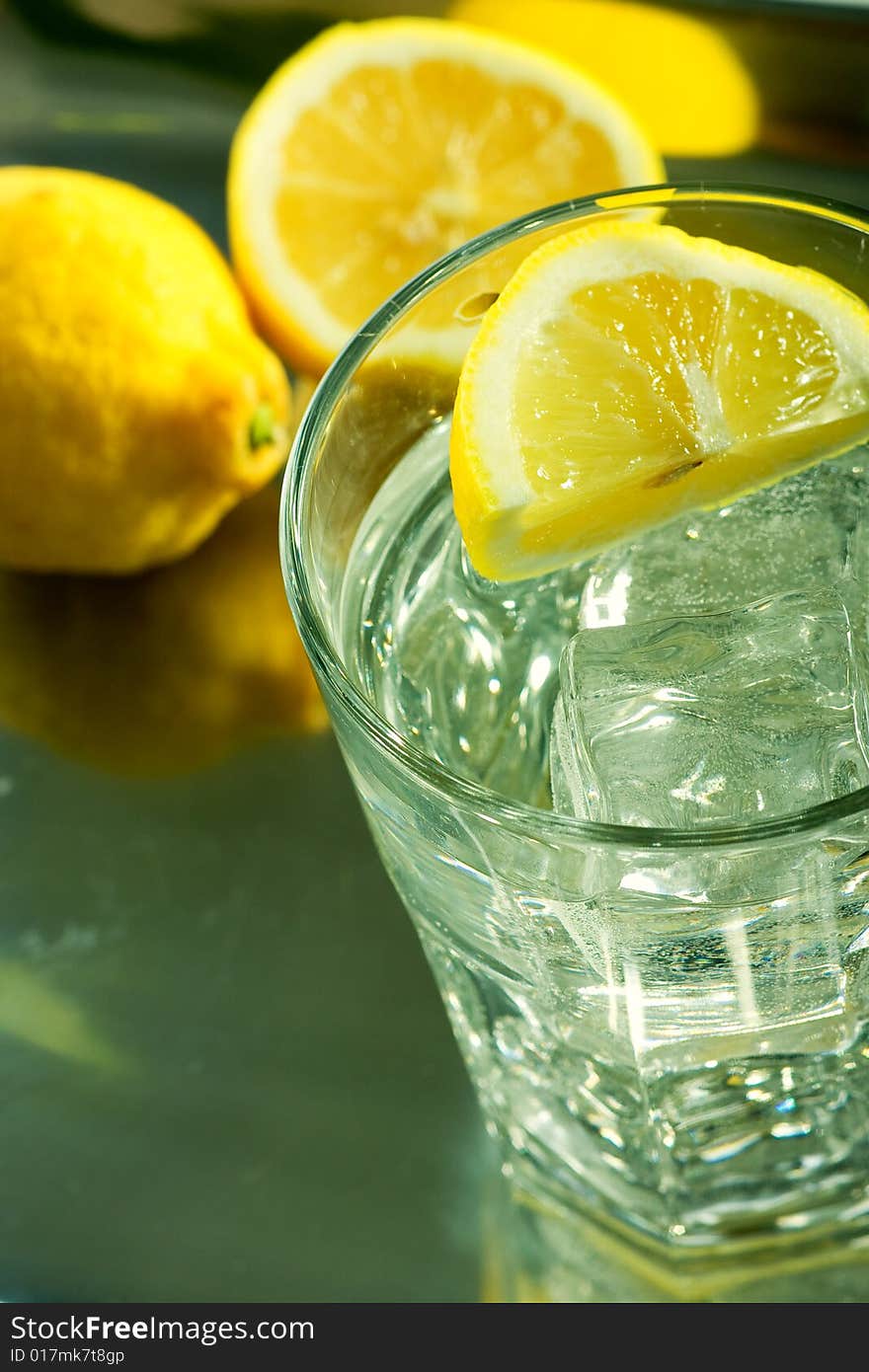 Glass of fresh water with cubes of ice and lemon