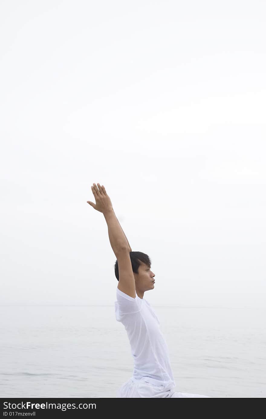 A young man practicing yoga at the beach. A young man practicing yoga at the beach