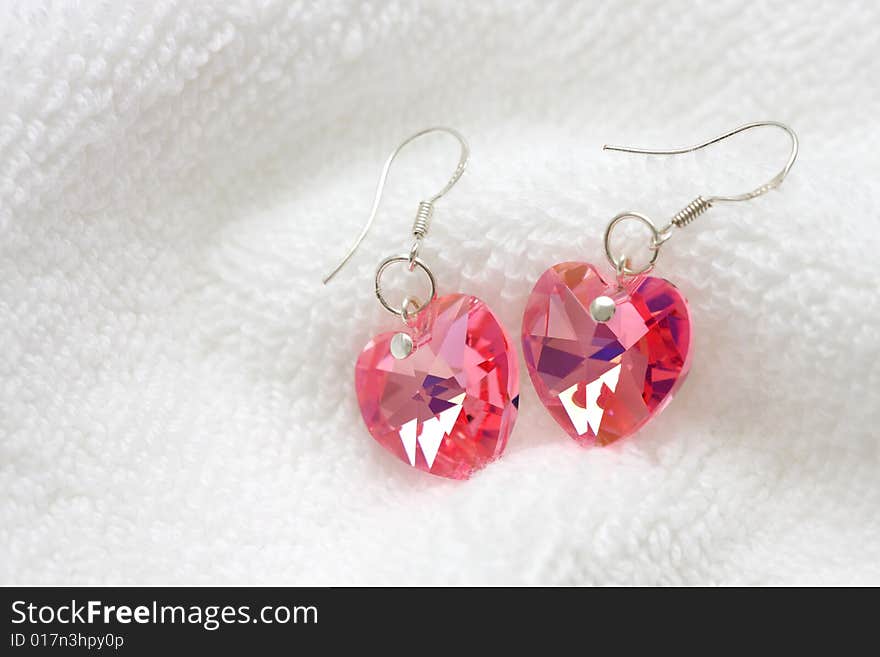 A pair of pink earrings put on white cotton cloth.