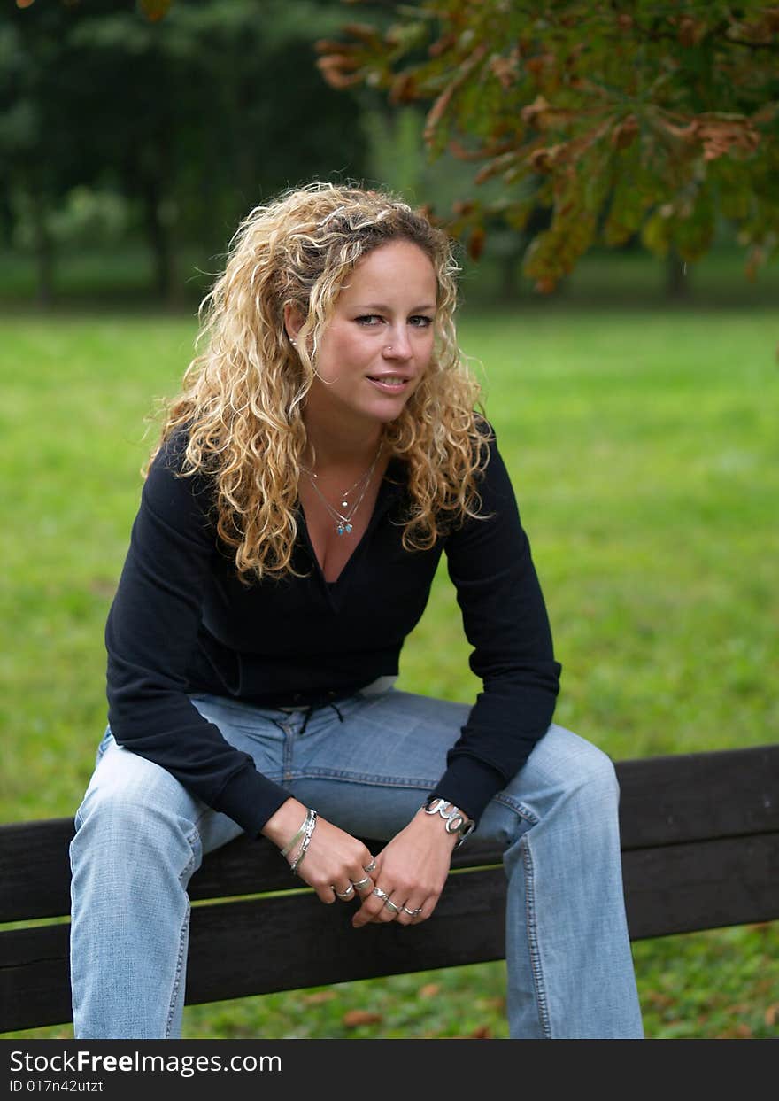 Curly girl sitting on bench in park. Curly girl sitting on bench in park