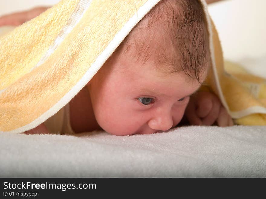 Newborn baby under towel spying on surrounding world