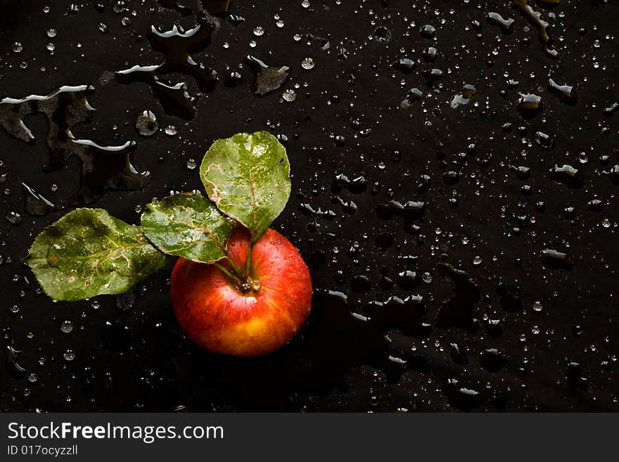 Wet red apple with green leafs on a bladk background. Wet red apple with green leafs on a bladk background