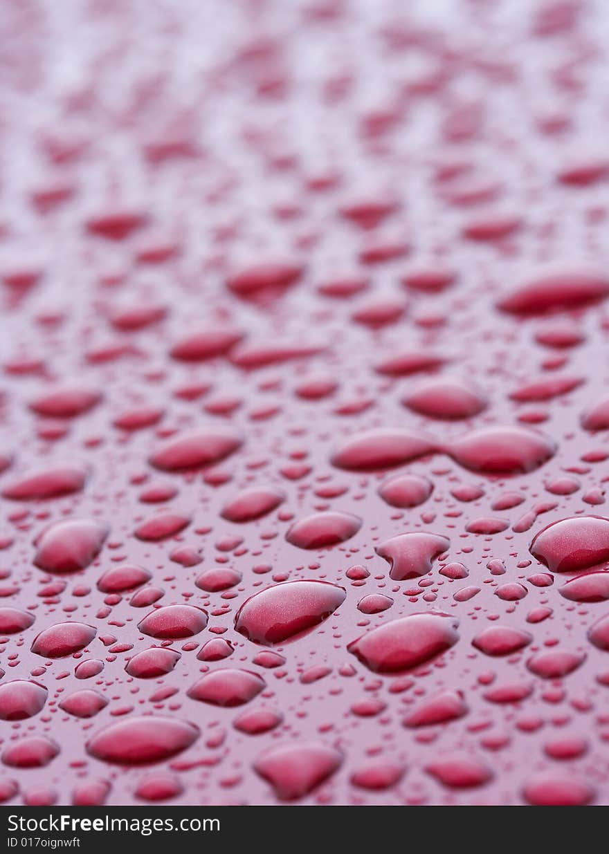 A picture of water drops on a red metal surface. A picture of water drops on a red metal surface