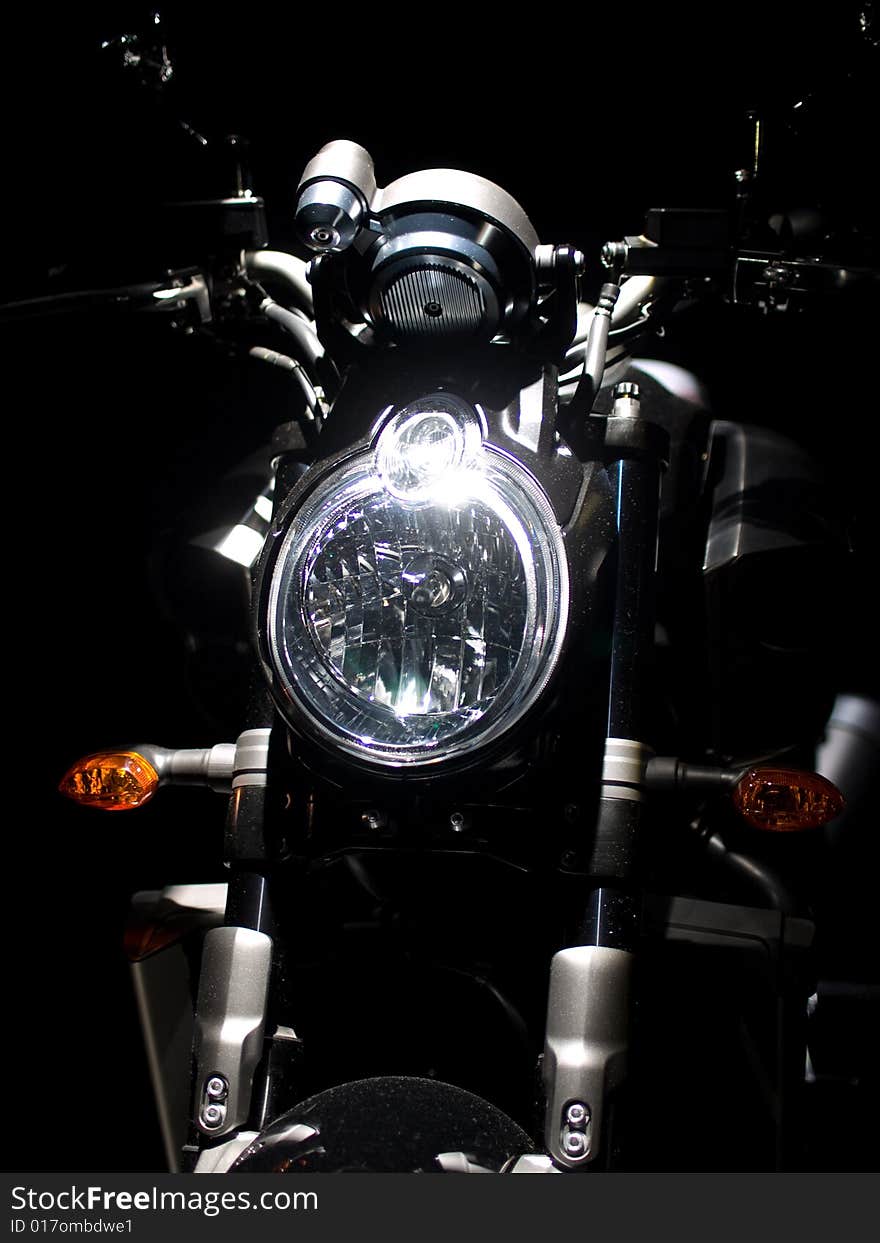 Headlight of new legend bike against a dark background. Headlight of new legend bike against a dark background.