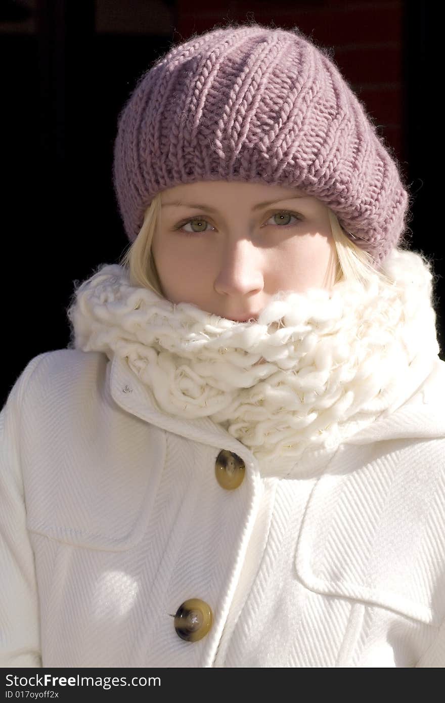 Attractive young blonde woman wearing magenta knit hat, white knit scarf and winter coat. Attractive young blonde woman wearing magenta knit hat, white knit scarf and winter coat.