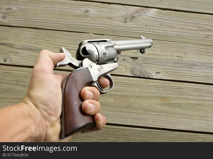 Cocked western style revolver being held in a hand pointed at a wall. Cocked western style revolver being held in a hand pointed at a wall