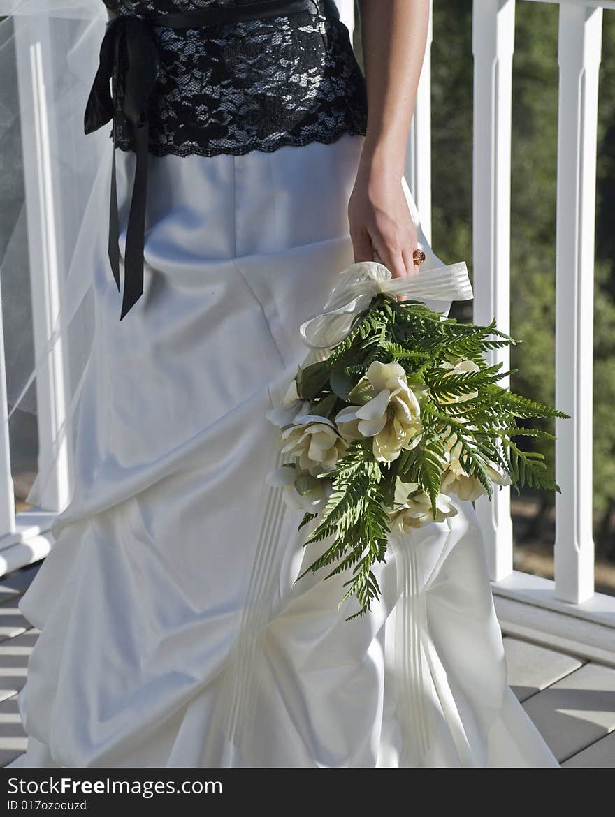 Bride with flowers standing outside on a deck