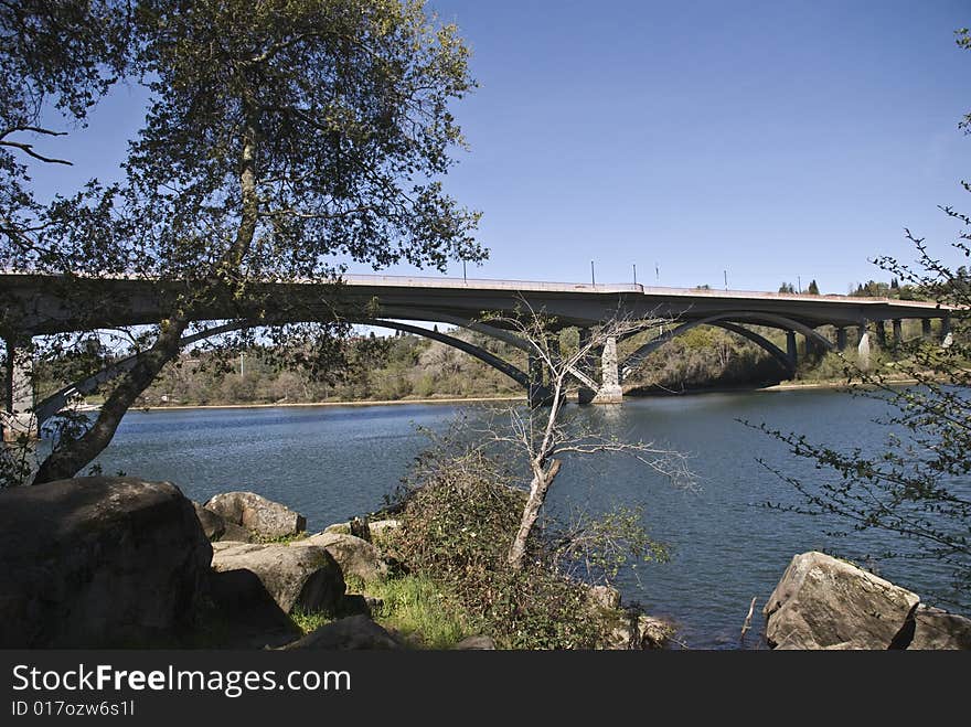 Bridge over river with blue sky and trees and rocks