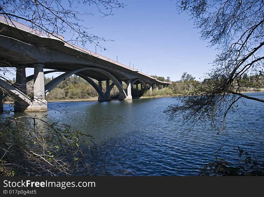 Cement bridge over river with trees and blue sky and water