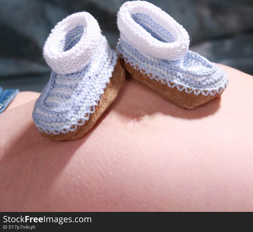 Baby booties sitting on top of the mommy baby belly