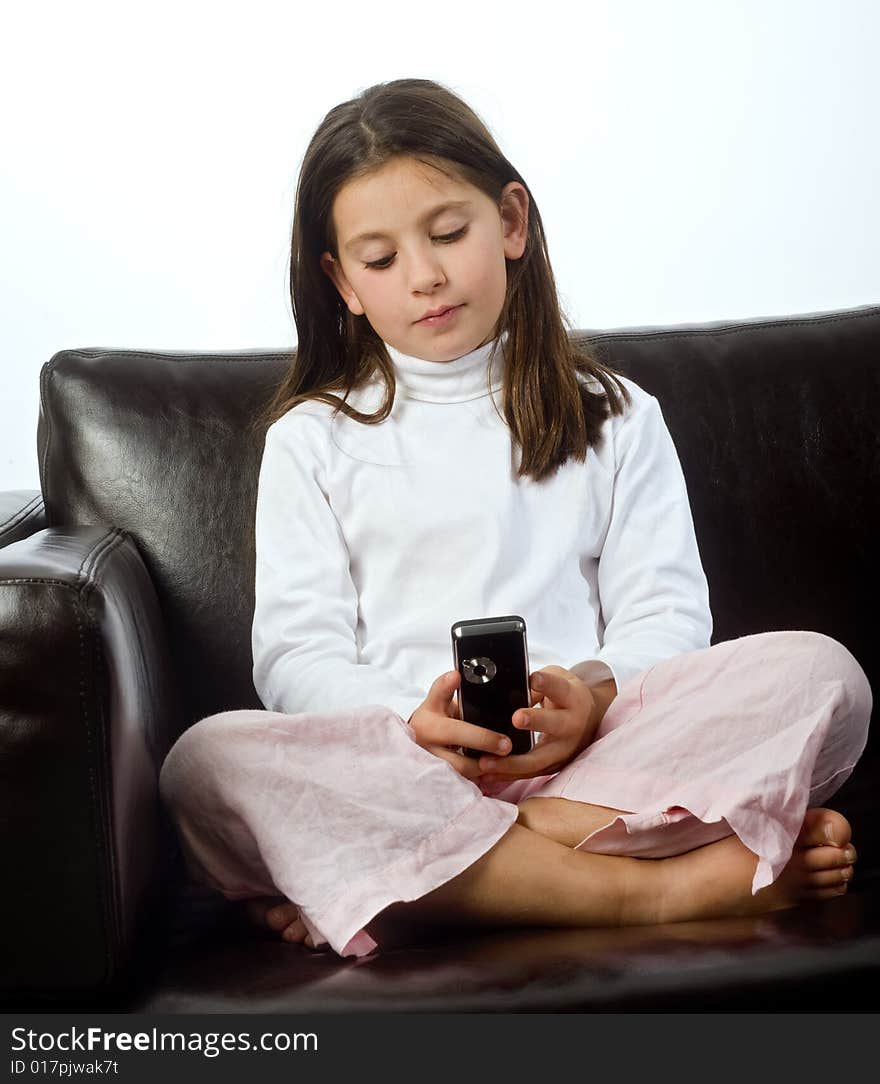 Young girl and cell phone on a sofa isolated on white