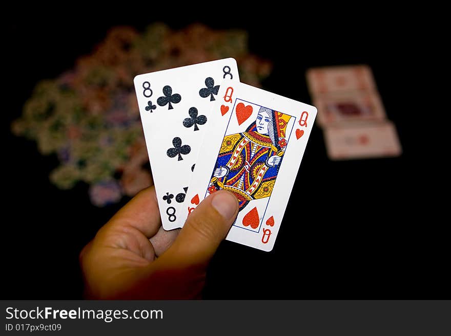 Poker table with chips  and two cards in hands