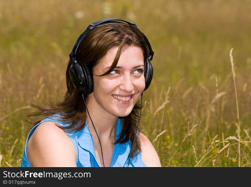 Attractive young woman listening music in a grass field. Attractive young woman listening music in a grass field