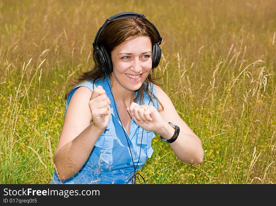 Attractive young woman listening music in a grass field. Attractive young woman listening music in a grass field