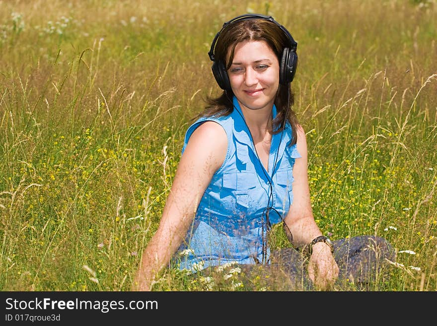 Attractive young woman listening music in a grass field. Attractive young woman listening music in a grass field