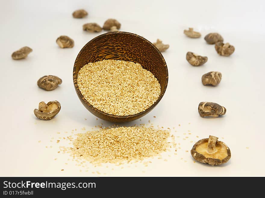 Sesame seeds in coconut bowl and dried shitake mushrooms isolated on white background. Sesame seeds in coconut bowl and dried shitake mushrooms isolated on white background