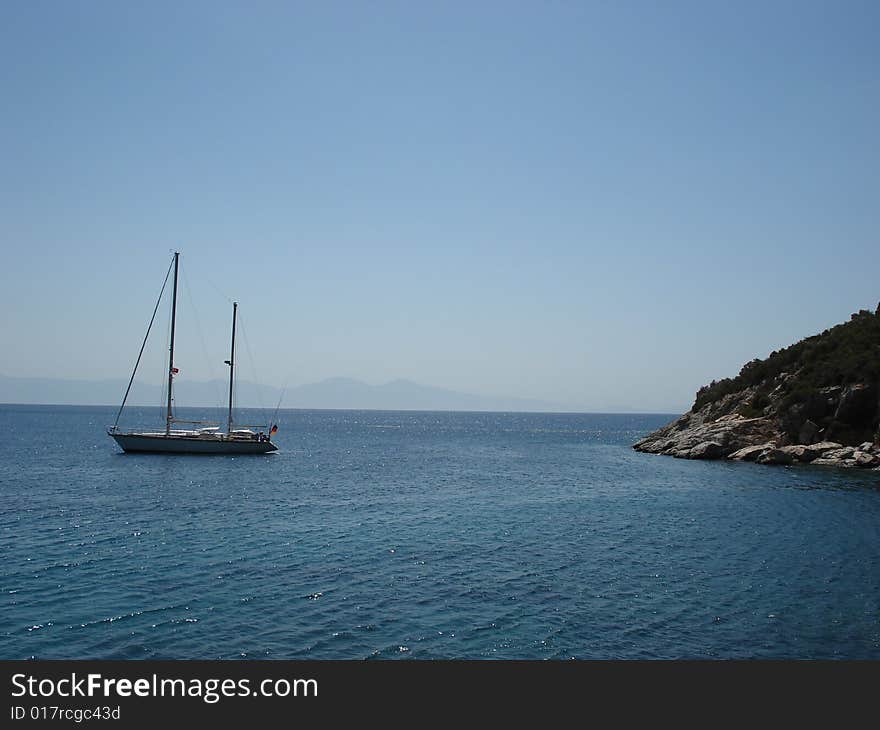 Small boat anchored in a gulf of a Mediterranean coast of Turkey on a perfect summer day. Small boat anchored in a gulf of a Mediterranean coast of Turkey on a perfect summer day