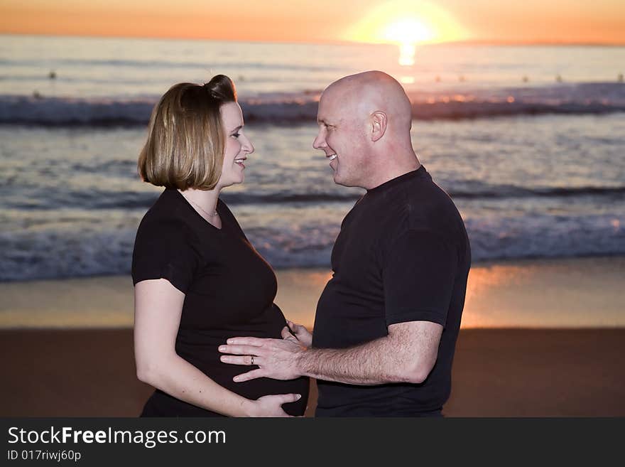 Pregnant Couple in Love on the Beach as Man touches Wfie's Belly