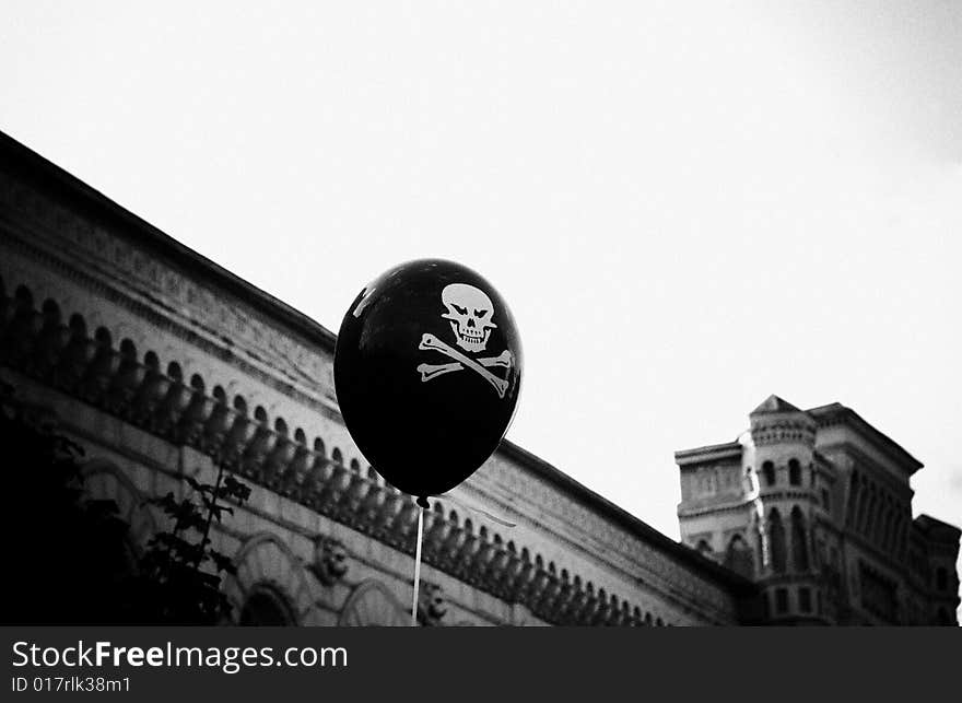 This black and white photograph represents a baloon with skull floating above boardwalk