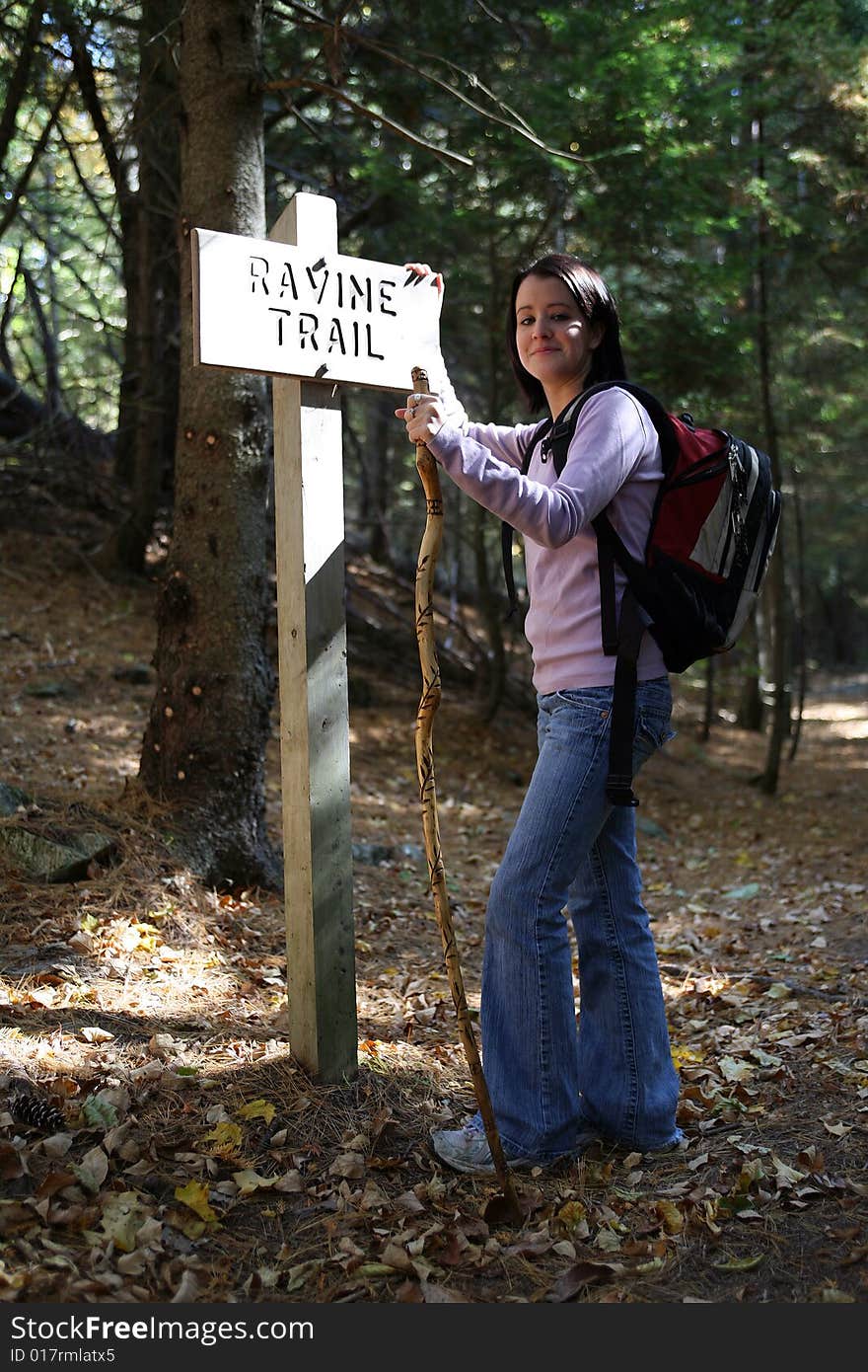 Pretty teenage hiker leaning against a sign post