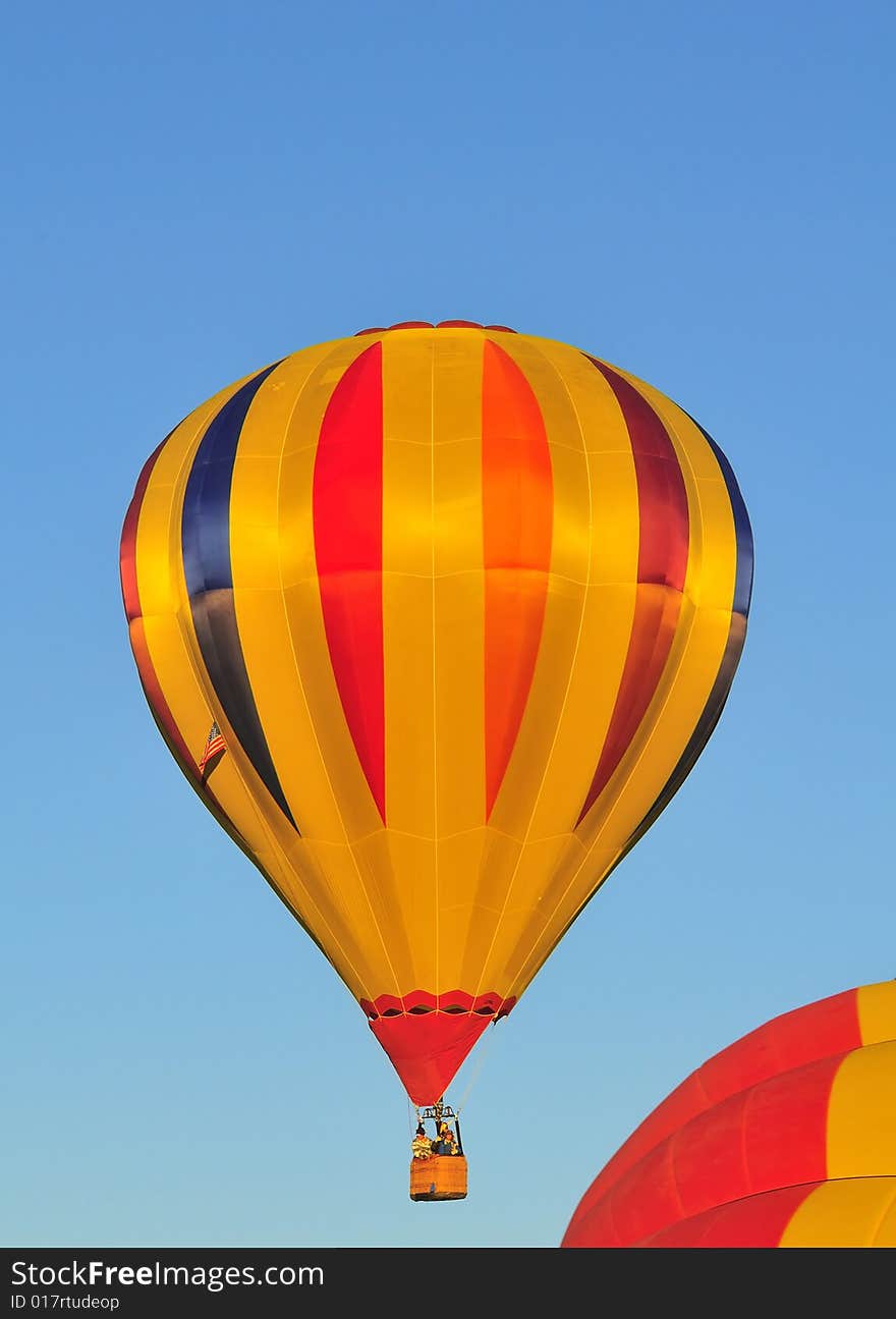 Hot air balloon Orange, gold and blue against blue sky