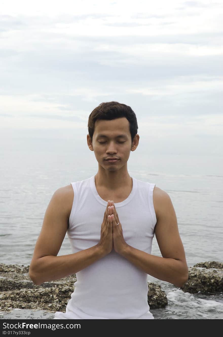 A young man meditating at the beach. A young man meditating at the beach