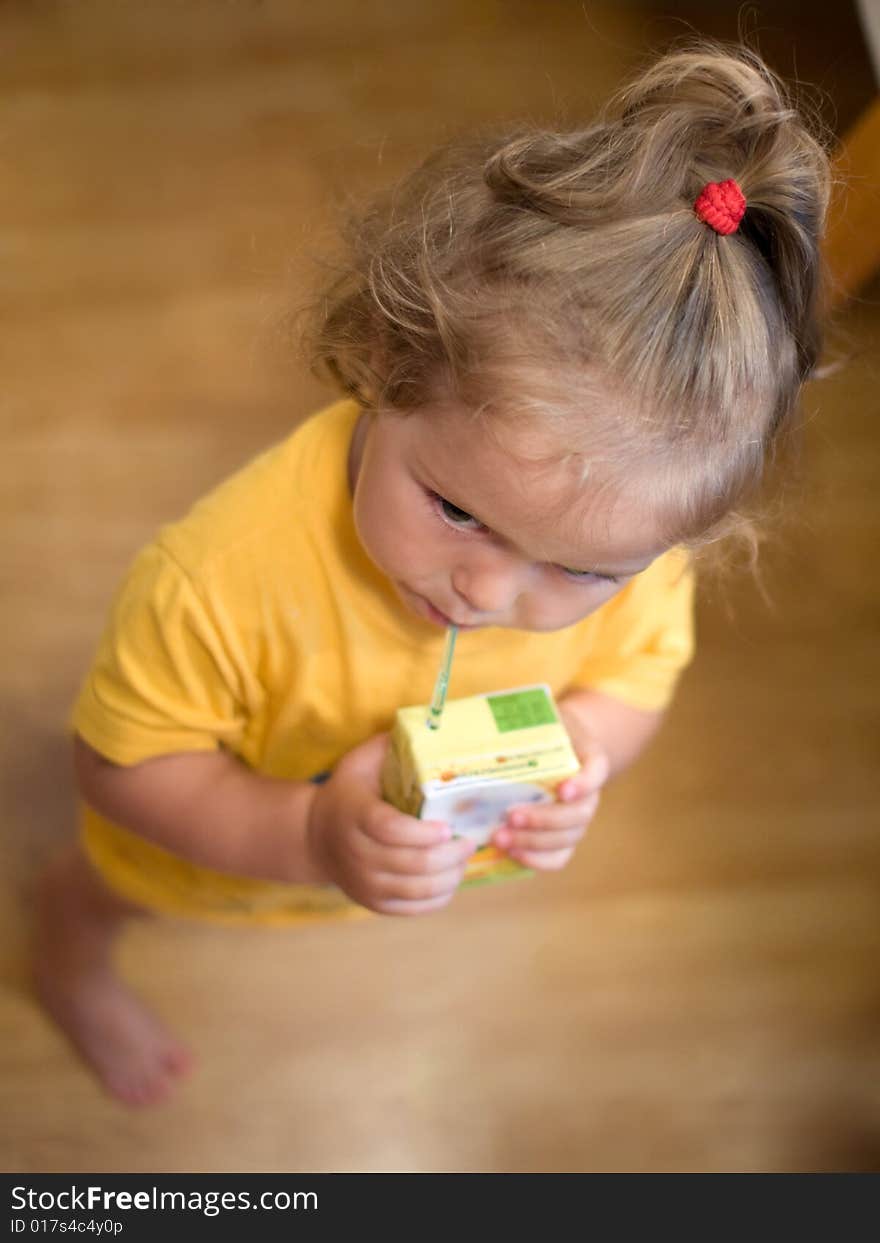 Beautiful little girl drinking juice