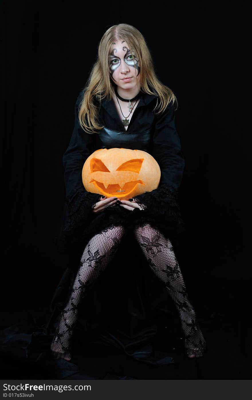 Nice girl with orange halloween pumpkin, on black background