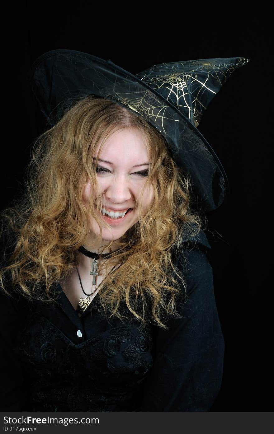 Cute young smiling halloween witch, on black background