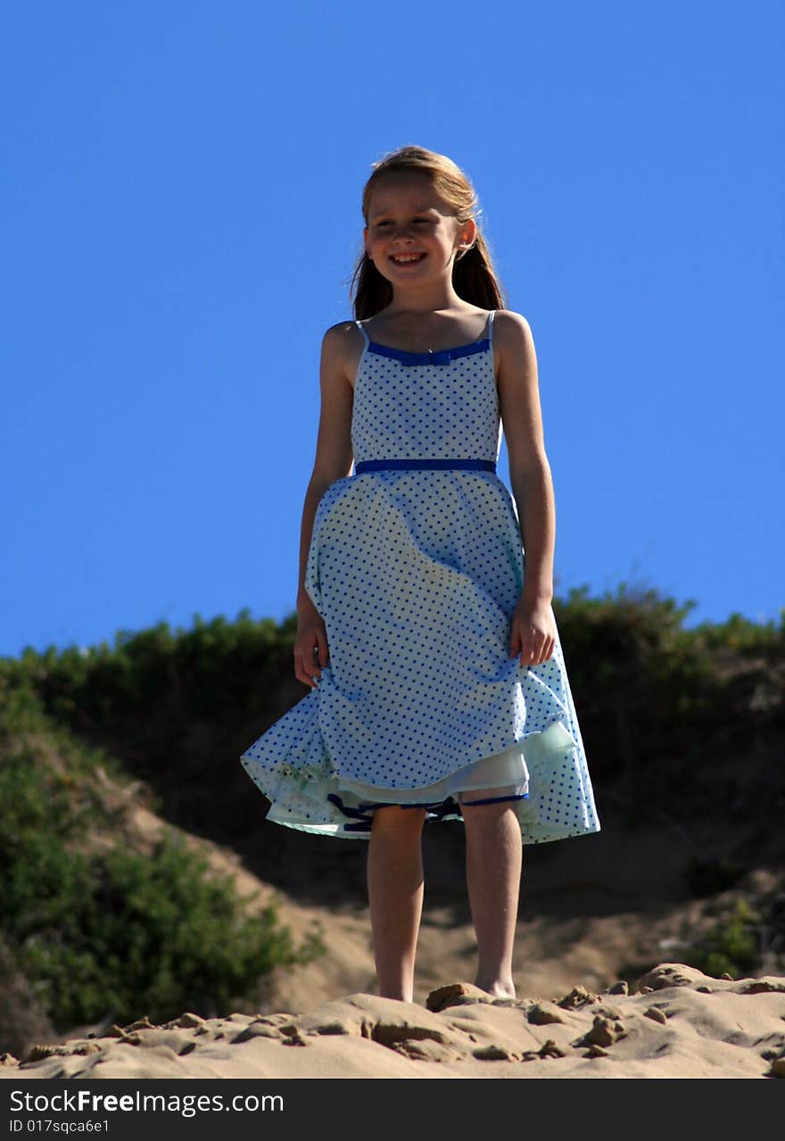 A white caucasian girl child playing on a sand dune on a hot summers day. A white caucasian girl child playing on a sand dune on a hot summers day