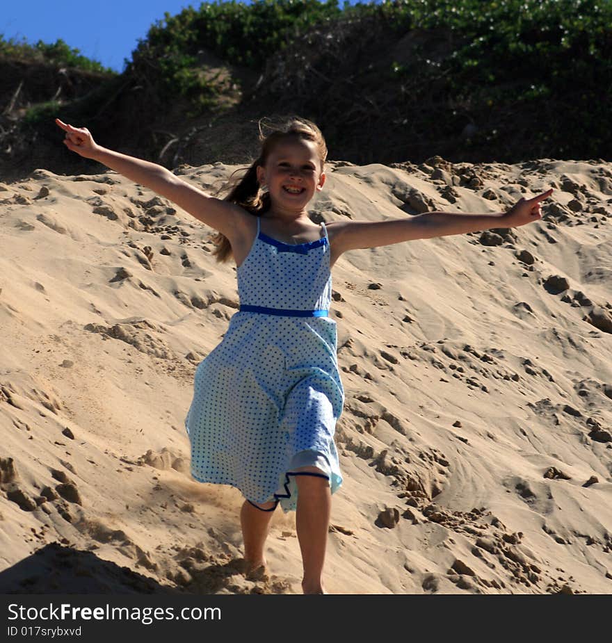 A white caucasian girl child playing on a sand dune on a hot summers day. A white caucasian girl child playing on a sand dune on a hot summers day