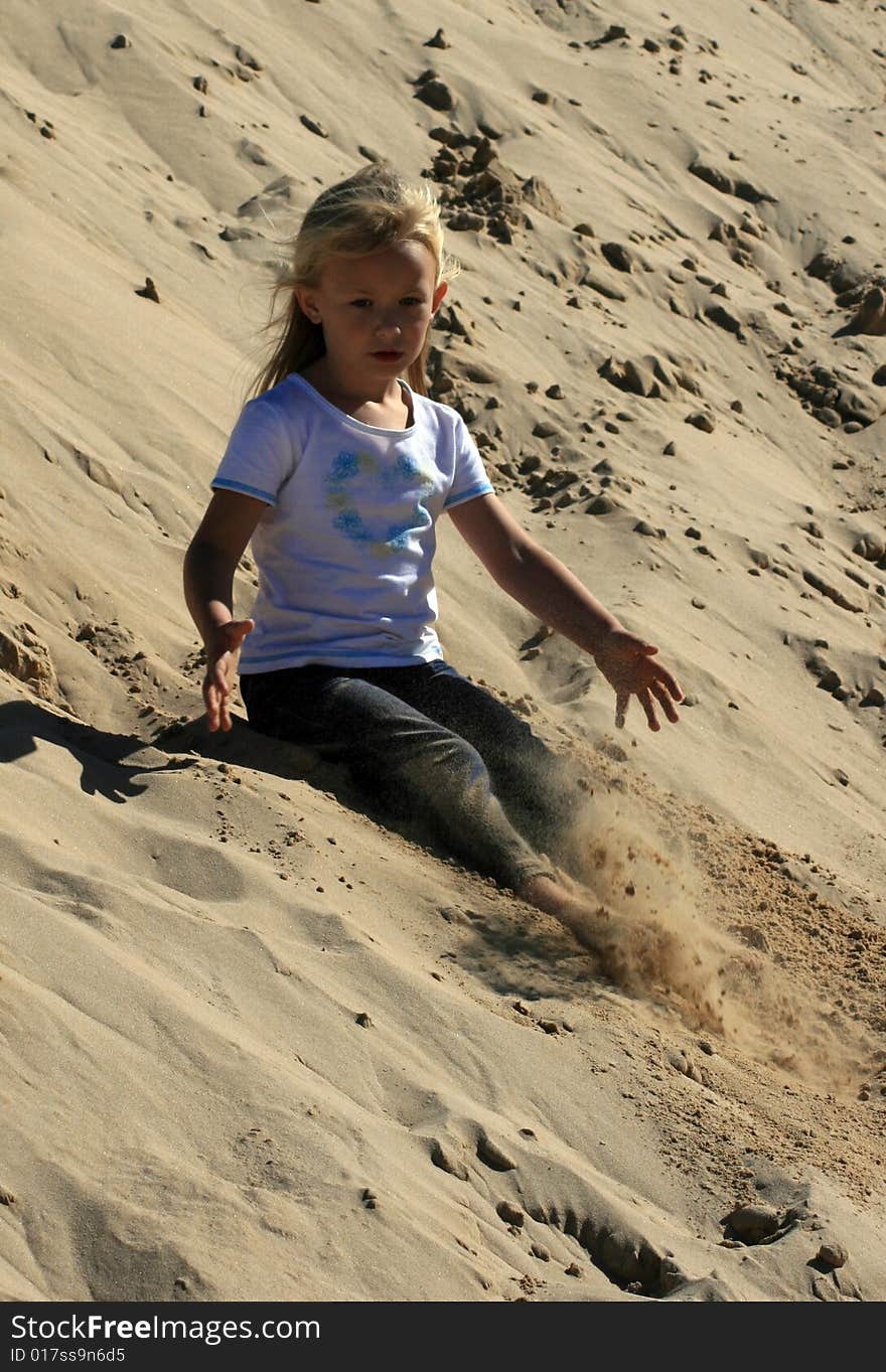 A white caucasian girl child playing on a sand dune on a hot summers day. A white caucasian girl child playing on a sand dune on a hot summers day