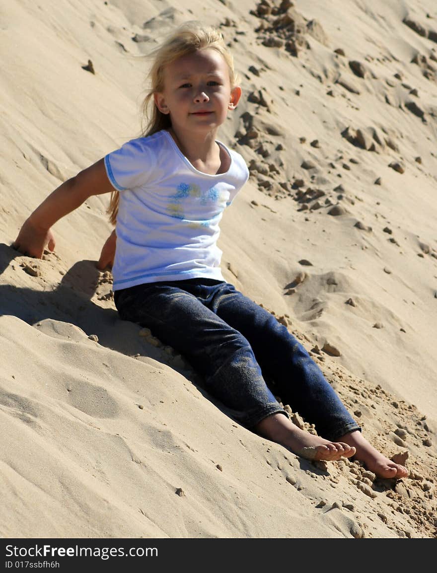 A white caucasian girl child playing on a sand dune on a hot summers day. A white caucasian girl child playing on a sand dune on a hot summers day