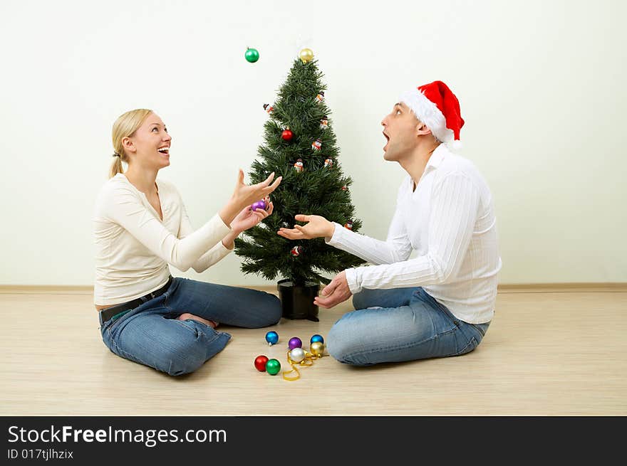 The pair juggles with spheres sitting at a Christmas pine. The pair juggles with spheres sitting at a Christmas pine