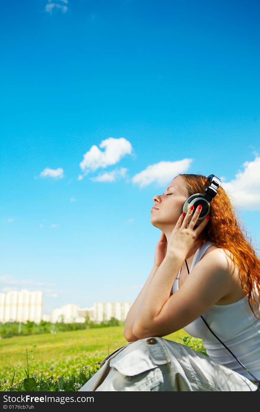 The girl in headphones listens to music in park. The girl in headphones listens to music in park