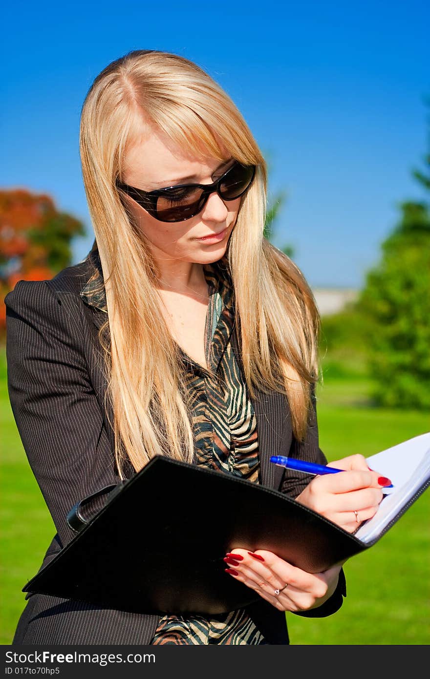 Blond businesswoman making a note in a folder. Blond businesswoman making a note in a folder