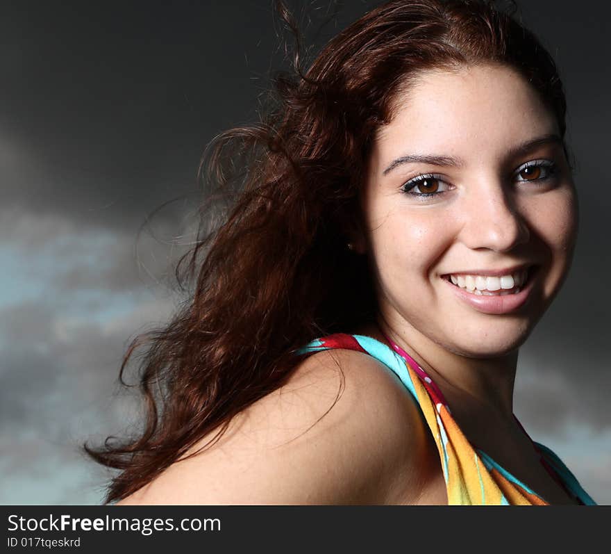 Young female smiling with cloudy sky background. Young female smiling with cloudy sky background