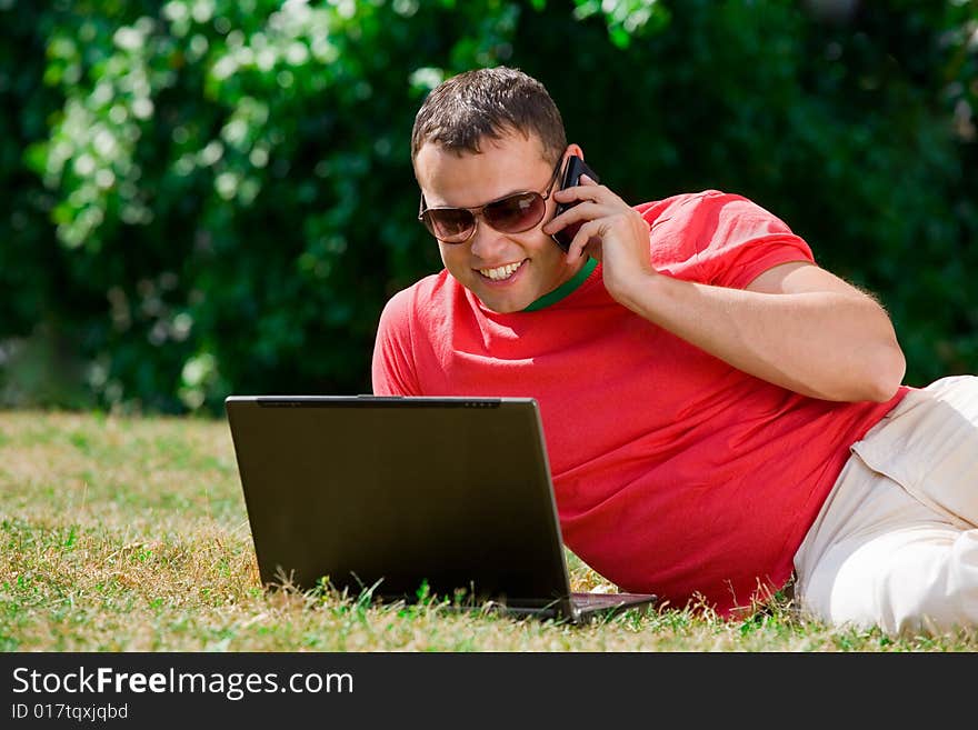 Young man working over a laptop computer and speaking phone